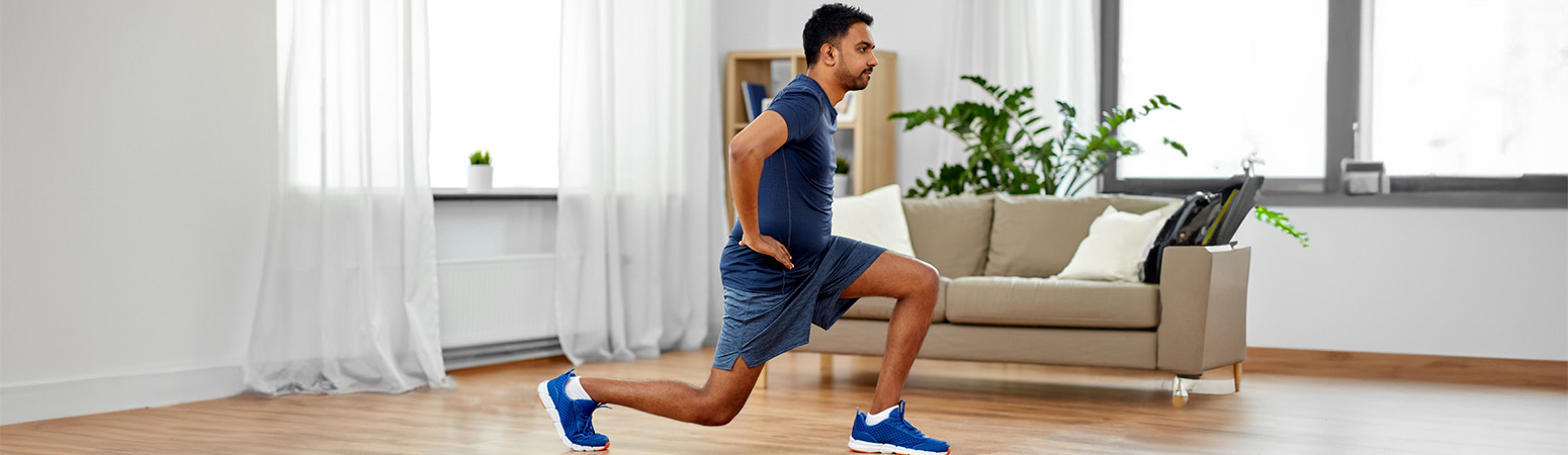 Man performing a reverse lunge at home, illustrating a physical therapy exercise for chondromalacia patella recovery.