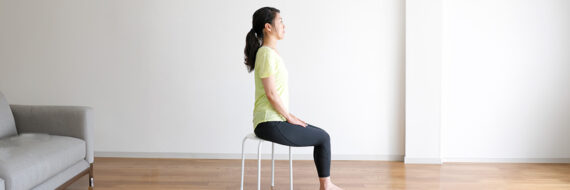 Person seated on a chair with hands resting on knees, demonstrating a physical therapy exercise for thoracic outlet syndrome.