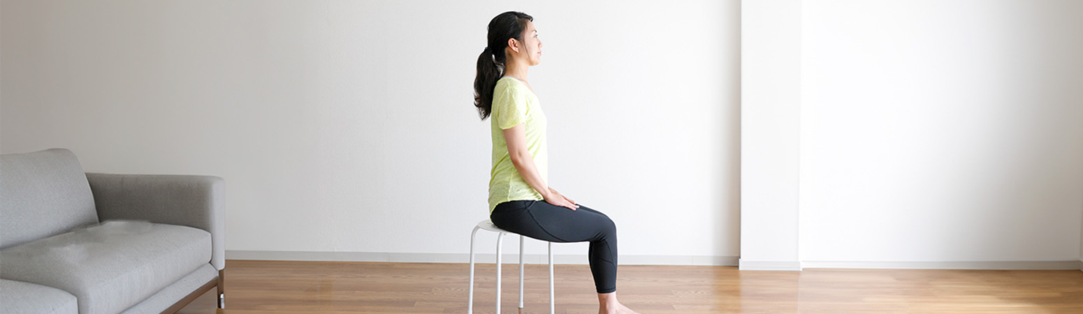 Person seated on a chair with hands resting on knees, demonstrating a physical therapy exercise for thoracic outlet syndrome.