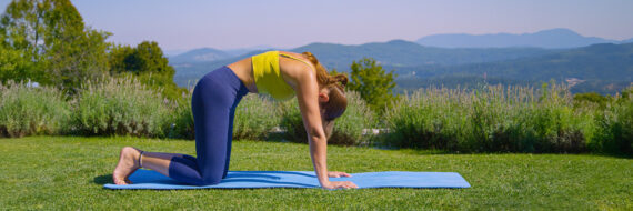 Person performing Cat Cow exercise outdoors for thoracic compression fracture recovery.