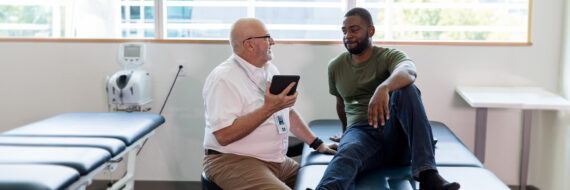 Rehabilitation professional using a tablet to demonstrate digital health skills to a patient during a consultation in a clinic.