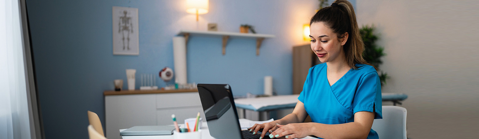 Therapist reviewing CPT codes for PT and OT billing on a laptop in a modern clinic office.