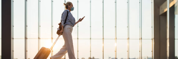 Travel therapist walking through an airport terminal with luggage, preparing for a new assignment.