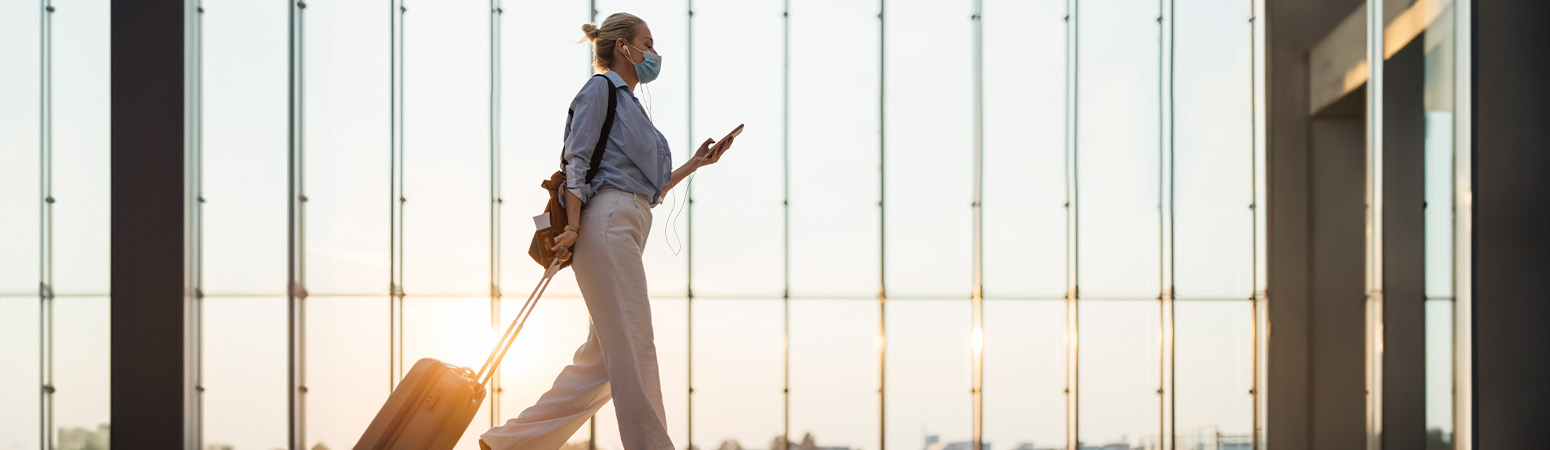 Travel therapist walking through an airport terminal with luggage, preparing for a new assignment.