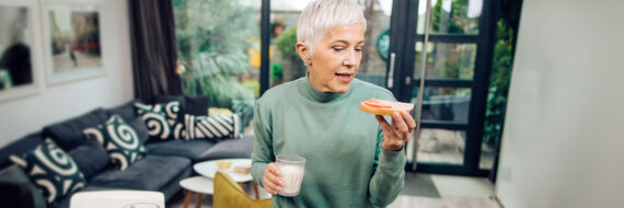 Older woman enjoying a snack while focusing on nutrition for bone health with a glass of milk and fruit.