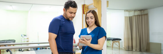 Physical therapist and patient reviewing a personalized care plan on a tablet, emphasizing digital patient engagement.