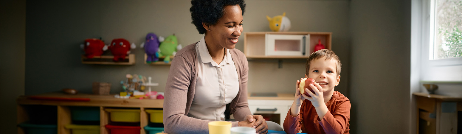 A therapist engages a young boy in sensory-based pediatric feeding therapy, with the child eating an apple during the session.