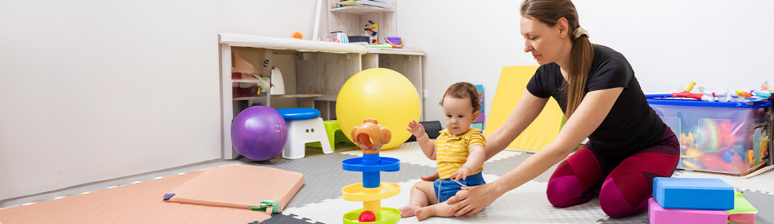 A therapist assists a child with cerebral palsy during physical therapy, encouraging motor skill development with colorful toys.