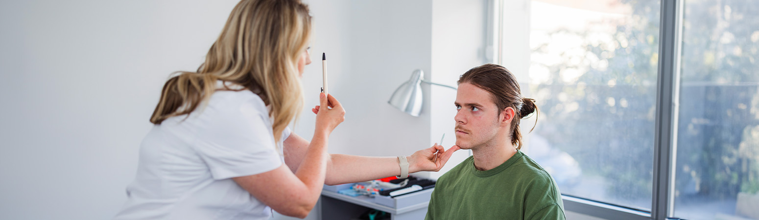 Healthcare professional performing an eye-tracking test on a young patient to assess post-concussion syndrome.